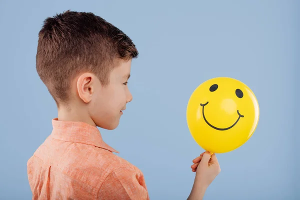 Criança. menino segura um balão amarelo com um sorriso . — Fotografia de Stock