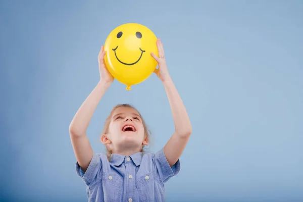 Szczęśliwy dzieciak dziewczyna trzyma się żółty balon z uśmiechem. — Zdjęcie stockowe