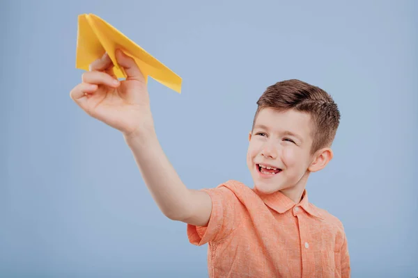 Smiling little boy holds yellow paper plane in his hand — 스톡 사진