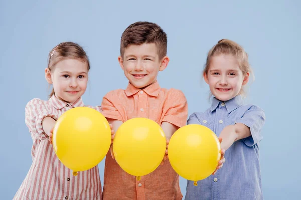 Três crianças menina e menino com balão amarelo com sorriso . — Fotografia de Stock