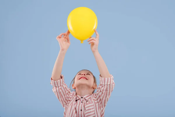 Menina criança feliz segura o balão amarelo vestido com camisa listrada , — Fotografia de Stock