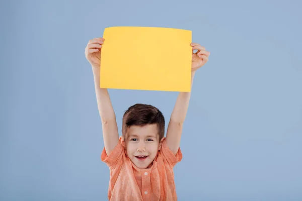 Criança feliz, menino com uma folha de papel amarelo para escrever , — Fotografia de Stock