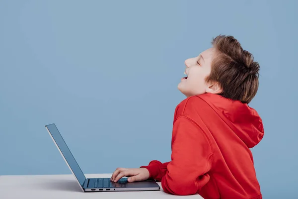 Gülümseyen çocuk ve kırmızı kazak dizüstü bilgisayarda oynuyor. — Stok fotoğraf