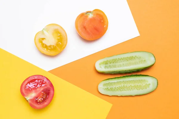 Tomates rojos y amarillos con pepino sobre blanco y amarillo —  Fotos de Stock