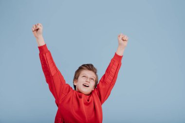 Elleri havada başarılı bir genç çocuğun portresi.
