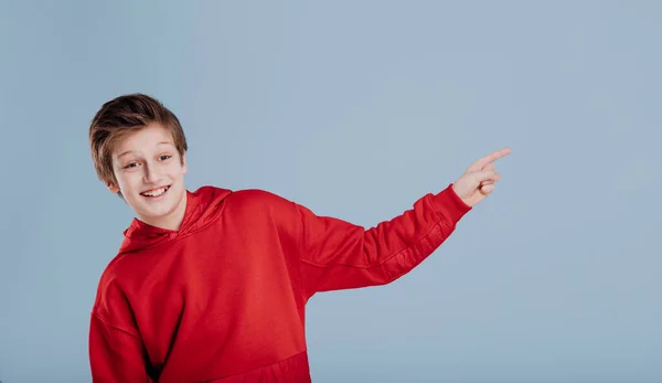 Cheerful schoolboy gesturing with finger in studio — Stock Photo, Image