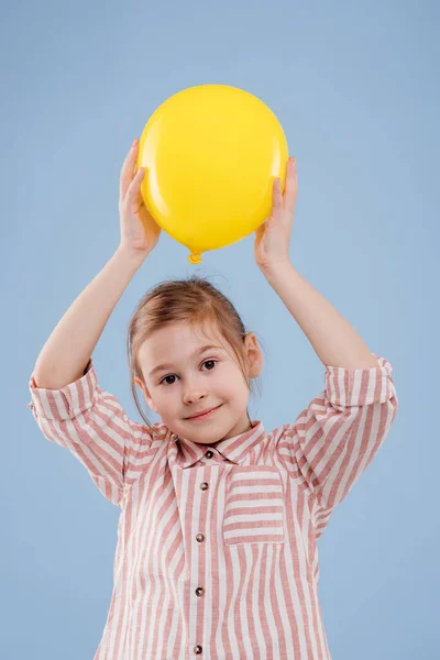 A menina segura o balão amarelo. olha para a câmera , — Fotografia de Stock