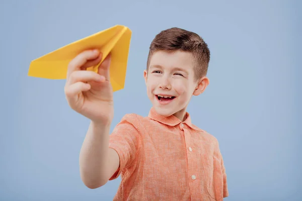 Szczęśliwy chłopiec trzyma żółty papierowy samolot w jego ręce, — Zdjęcie stockowe