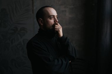 Pencereye bakan üzgün sakallı adam .