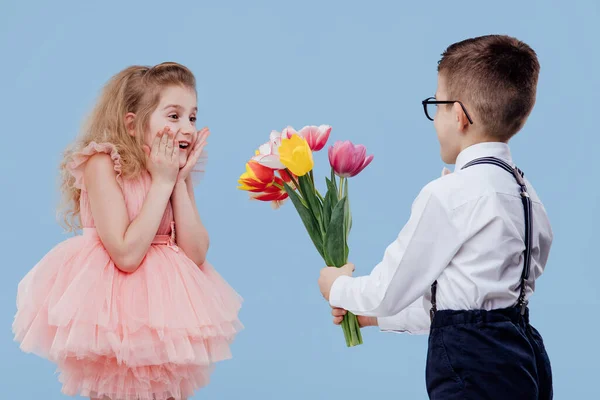 Dwa małe dzieci mały chłopiec wyciąga kwiaty do małej dziewczynki — Zdjęcie stockowe