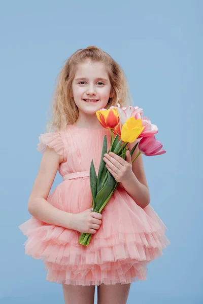 Des tulipes. petite fille avec des fleurs de printemps à la main, en robe rose — Photo