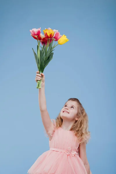 Smiling little girl picks up a bouquet of spring flowers — Stock Photo, Image