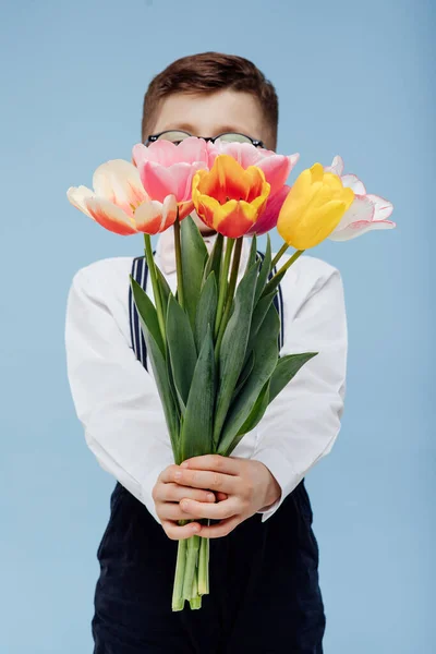 little boy hides his face with flowers,