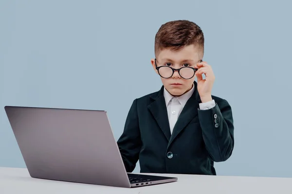 Schooljongen met bril met behulp van een laptop in studio — Stockfoto