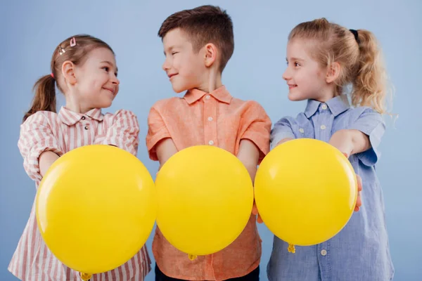 Três crianças felizes meninas e um menino com balões amarelos — Fotografia de Stock