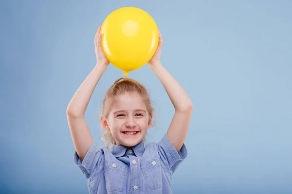 Szczęśliwy dziecko dziewczyna trzyma się żółty balon z uśmiechem. — Zdjęcie stockowe