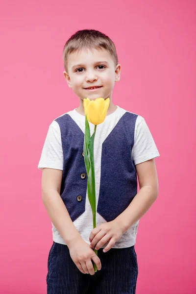 一个微笑的小男孩拿着一朵黄色郁金香花的画像 — 图库照片