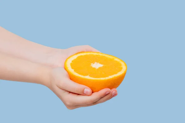 Primer plano, medio naranja en las manos de la chica —  Fotos de Stock