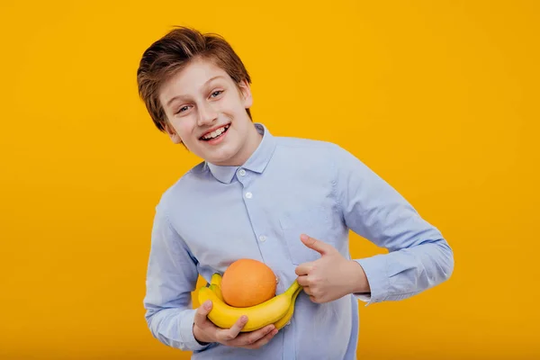 Preteen nice boy with fruits in hand, banana and orange — Stock Photo, Image