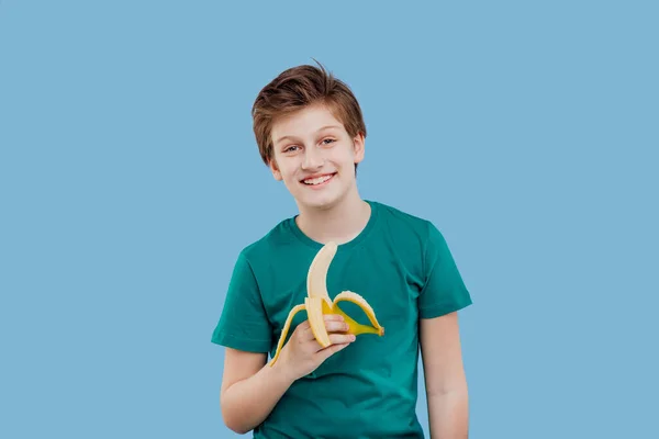 Souriant préadolescent garçon avec une banane dans sa main vert t-shirt — Photo