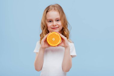 Elinde portakalla gülümseyen küçük bir kız.,