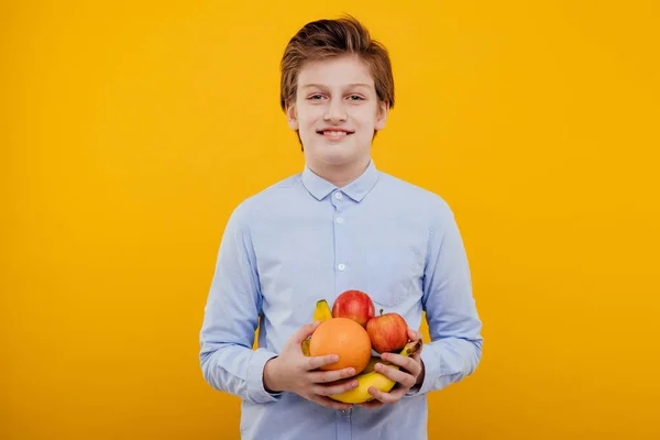 Hermoso niño preadolescente con fruta en la mano, mira a la cámara —  Fotos de Stock