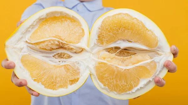 Buah pomelo dipotong di tangan, terisolasi pada kuning — Stok Foto