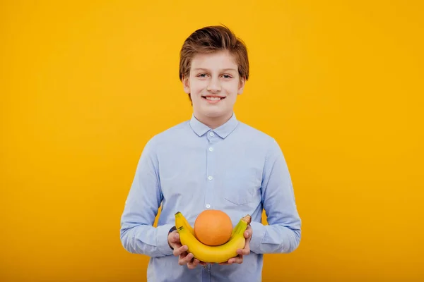 Niño preadolescente agradable con fruta mira a la cámara —  Fotos de Stock