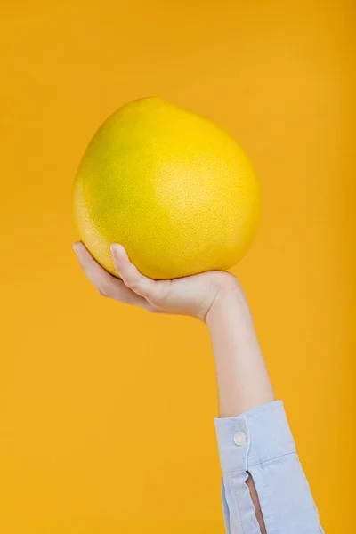 Primer plano pomelo en mano, aislado en amarillo —  Fotos de Stock