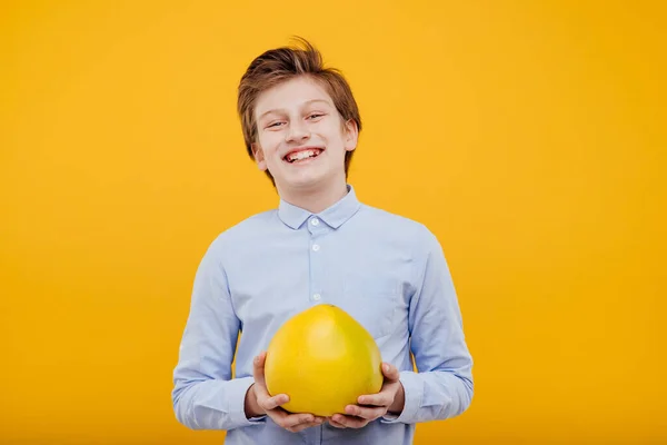 Preadolescente feliz chico con pomelo fruta en la mano —  Fotos de Stock