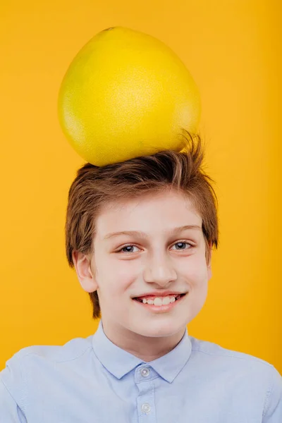 Retrato preteen criança menino com pomelo fruta na cabeça — Fotografia de Stock