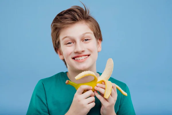 Souriant jeune garçon avec une banane dans sa main t-shirt vert — Photo