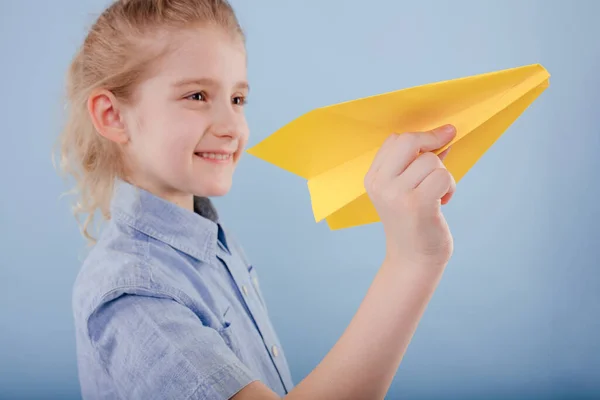 Close up, happy kid girl holds yellow paper plane in his hand, — Stock Photo, Image