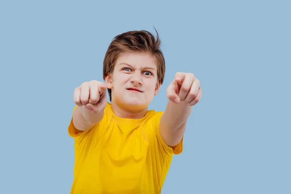 Aggressive schoolboy gesturing in studio on yellow background — Stockfoto