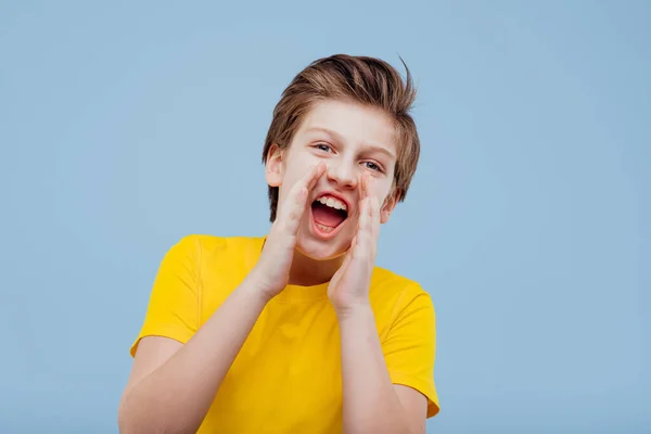 Adolescent heureux criant en studio sur fond bleu — Photo