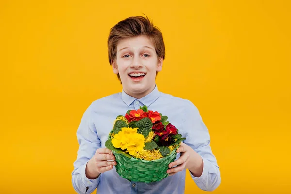 Adolescent heureux avec des fleurs en studio sur fond jaune — Photo