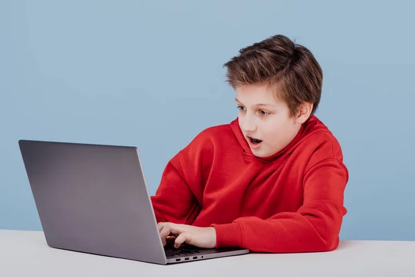 Excited boy in red sweatshirt playing on laptop — Stok fotoğraf