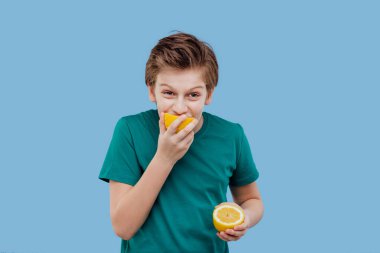 Çocuk taze bir limon tadı, ekşi bir tat, yüzünü buruşturuyor.,