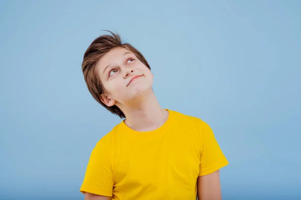 Heureux jeune garçon lève les yeux en jaune t-shirt — Photo
