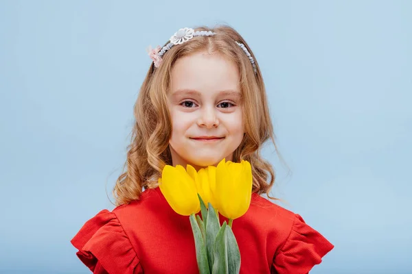 Portrait de petite fille souriante avec trois tulipes jaunes — Photo