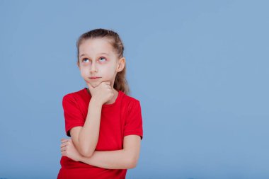 Kırmızı tişörtlü çocuk çenesine dokunuyor ve kafasını kaldırıyor.