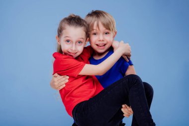 Stüdyoda kızı taşıyan neşeli çocuk mavi arka planda izole edilmiş.,