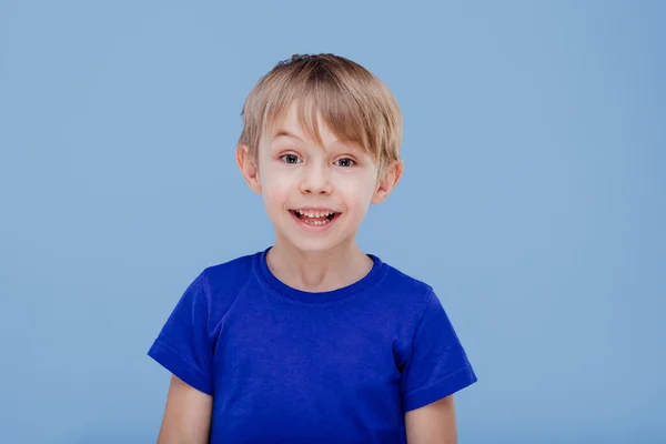 Leuk hapy kind kijkt naar de camera gekleed in blauw T-shirt, — Stockfoto