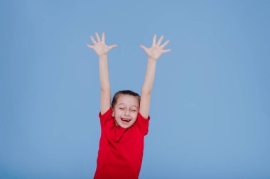 Kolları mavi arka planda büyümüş pozitif küçük kız.