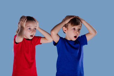 Şaşkın küçük kız ve oğlan gündelik giysiler içinde kafa tutuyorlar.