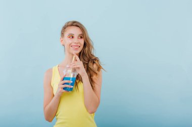 Neşeli makyajlı gülümseyen kadın plastik bardakta mavi içki tutuyor.