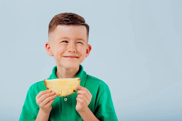 Szczęśliwy chłopiec ma kawałek ananasa w ręku. — Zdjęcie stockowe