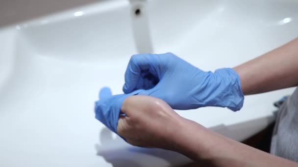 Женщина руки носить медицинские латексные перчатки с умывальником фоне . — стоковое видео