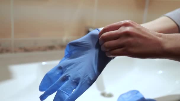 Woman hands wear medicinal latex gloves with a washbasin background — Stock Video
