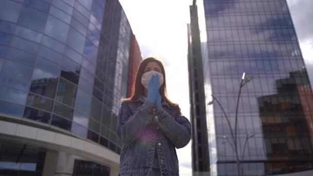 Аплодисменты. Женщина в перчатках и медицинской маске аплодирует городскому фону . — стоковое видео